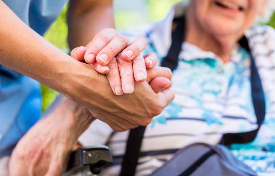 a carer holding an elderly persons hand