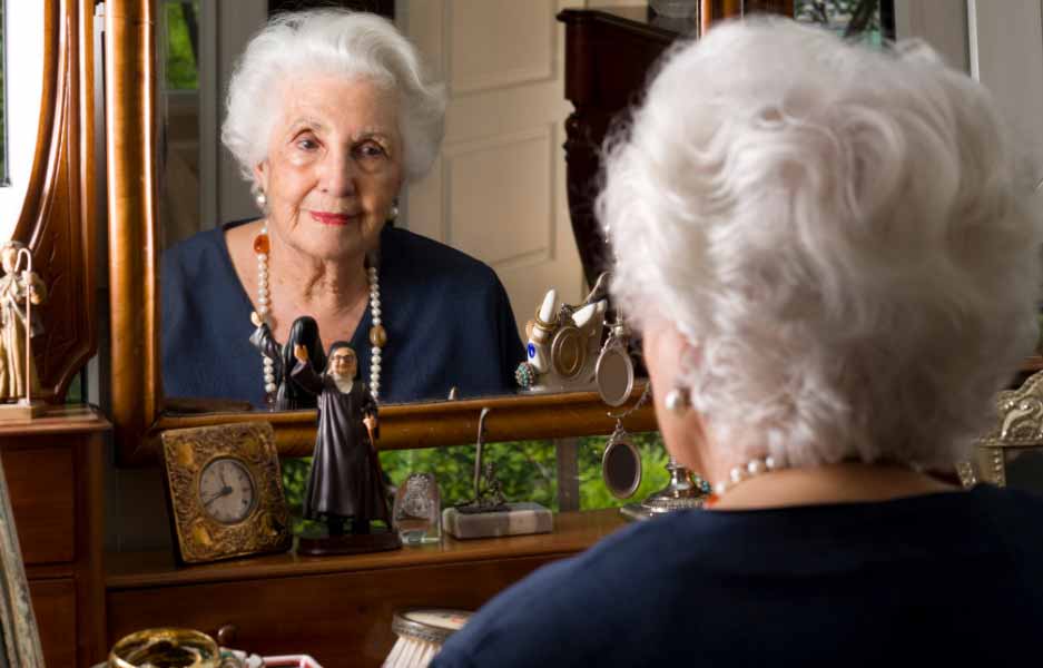 an elderly woman looking in the mirror